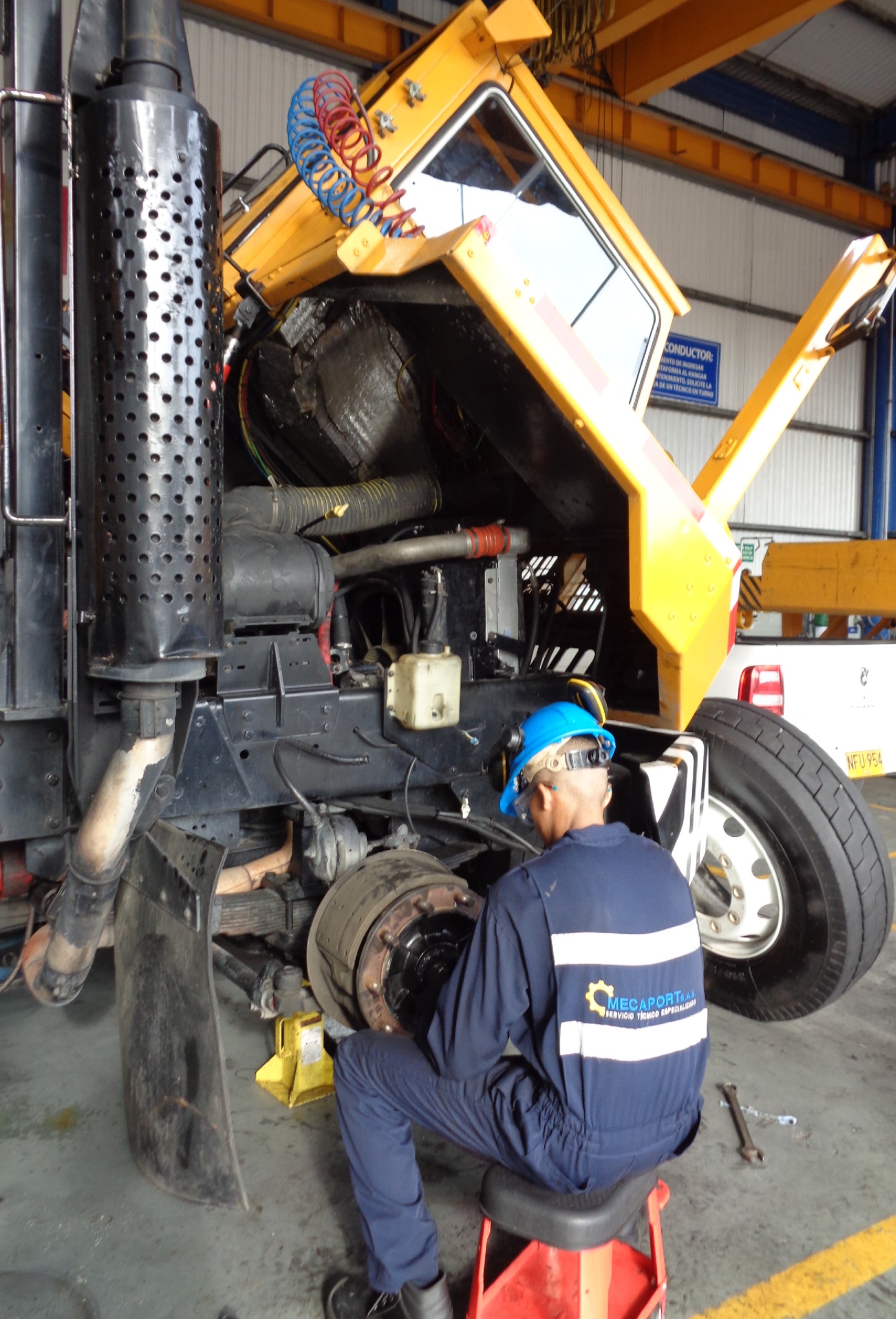 Técnico Mecaport con overol corporativo realizando mantenimiento de camión industrial en taller